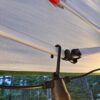 Close-up of a hook retained in a Brightech string light and hanging from a canopy frame. Lights and canopy not included.