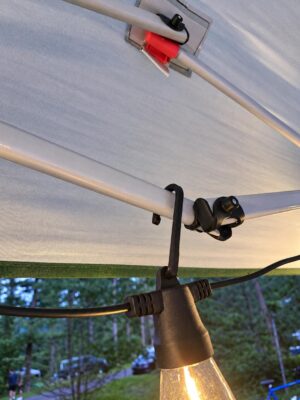 Close-up of a hook retained in a Brightech string light and hanging from a canopy frame. Lights and canopy not included.